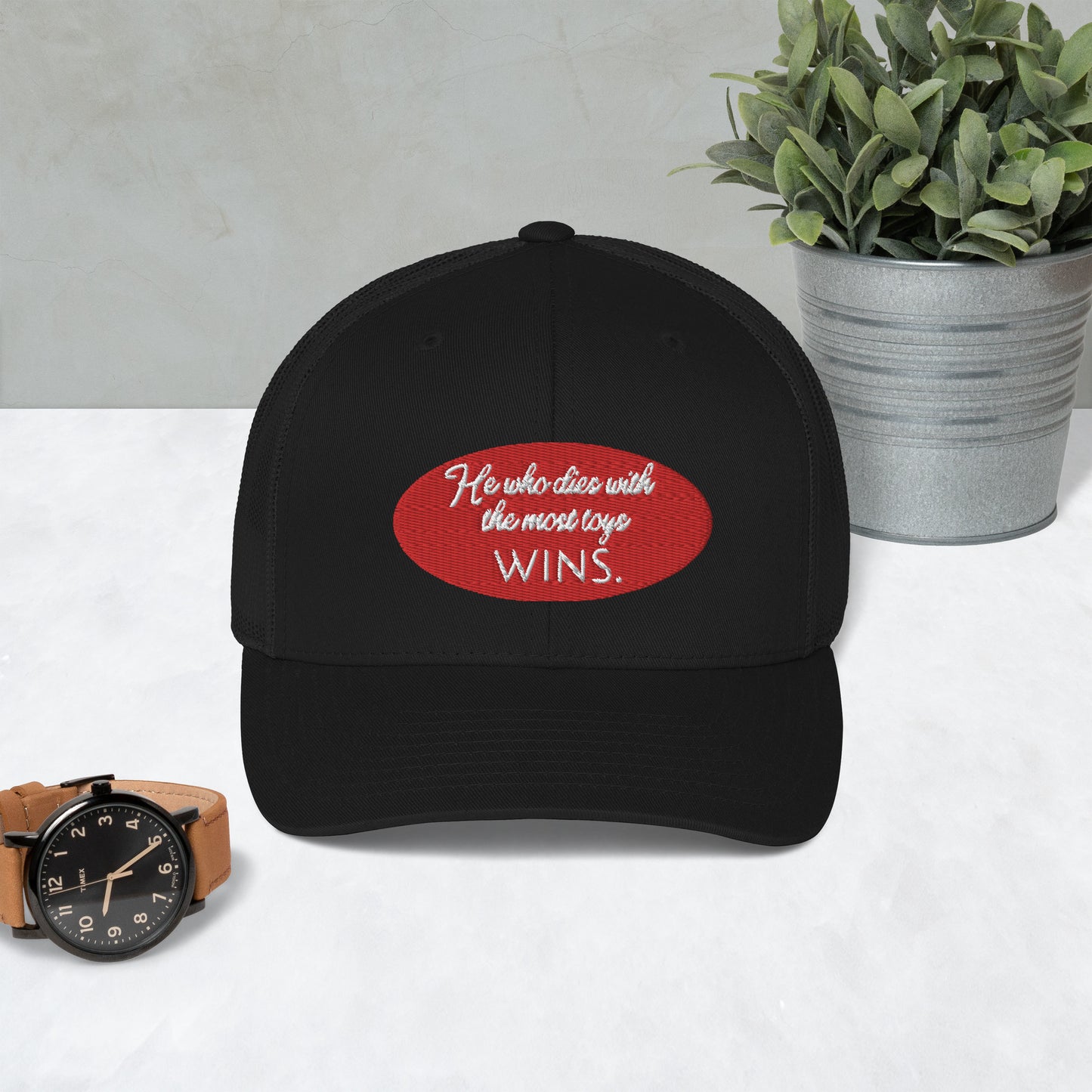 He who dies with the most toys WINS. Trucker Cap