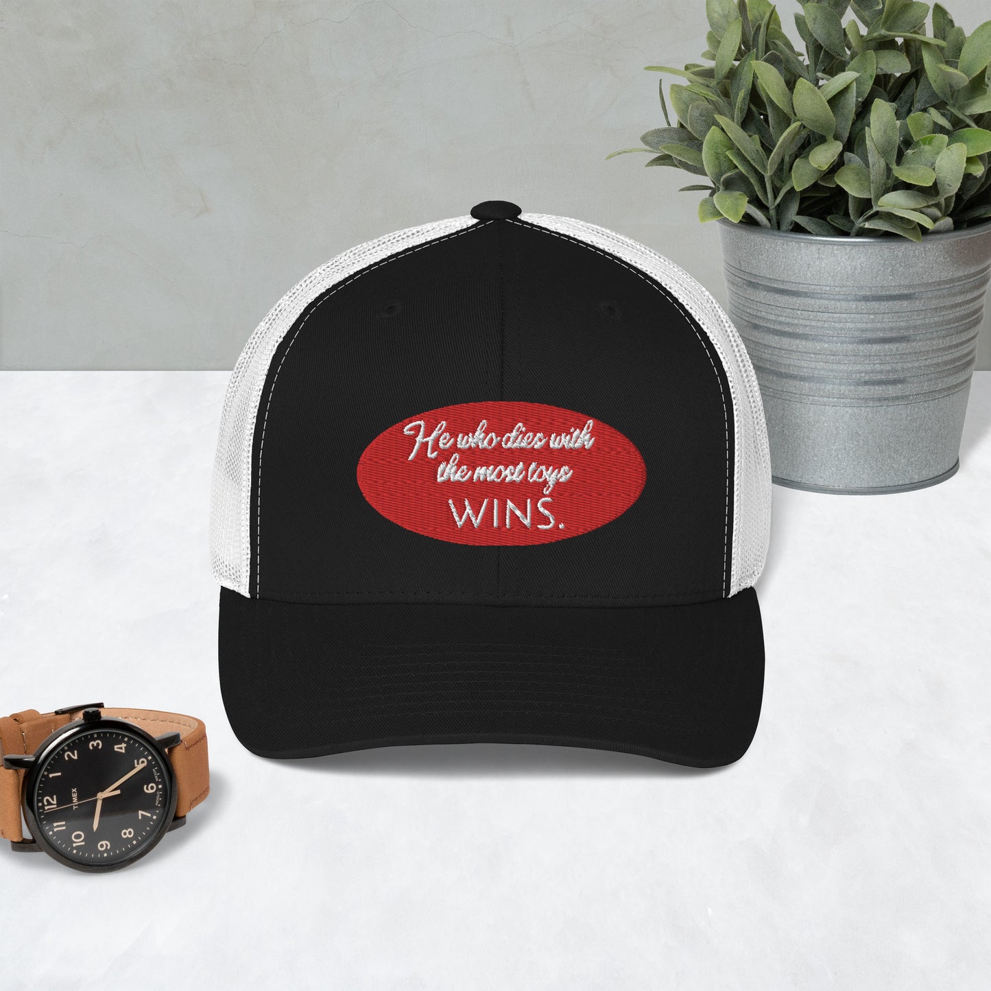 He who dies with the most toys WINS. Trucker Cap