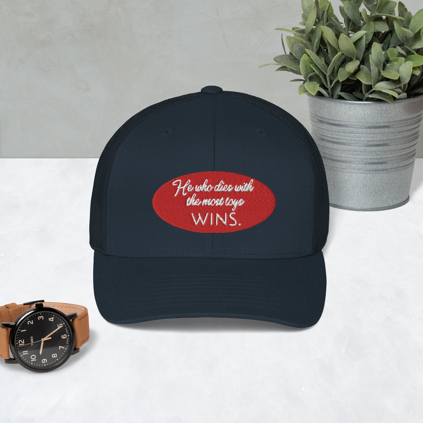 He who dies with the most toys WINS. Trucker Cap