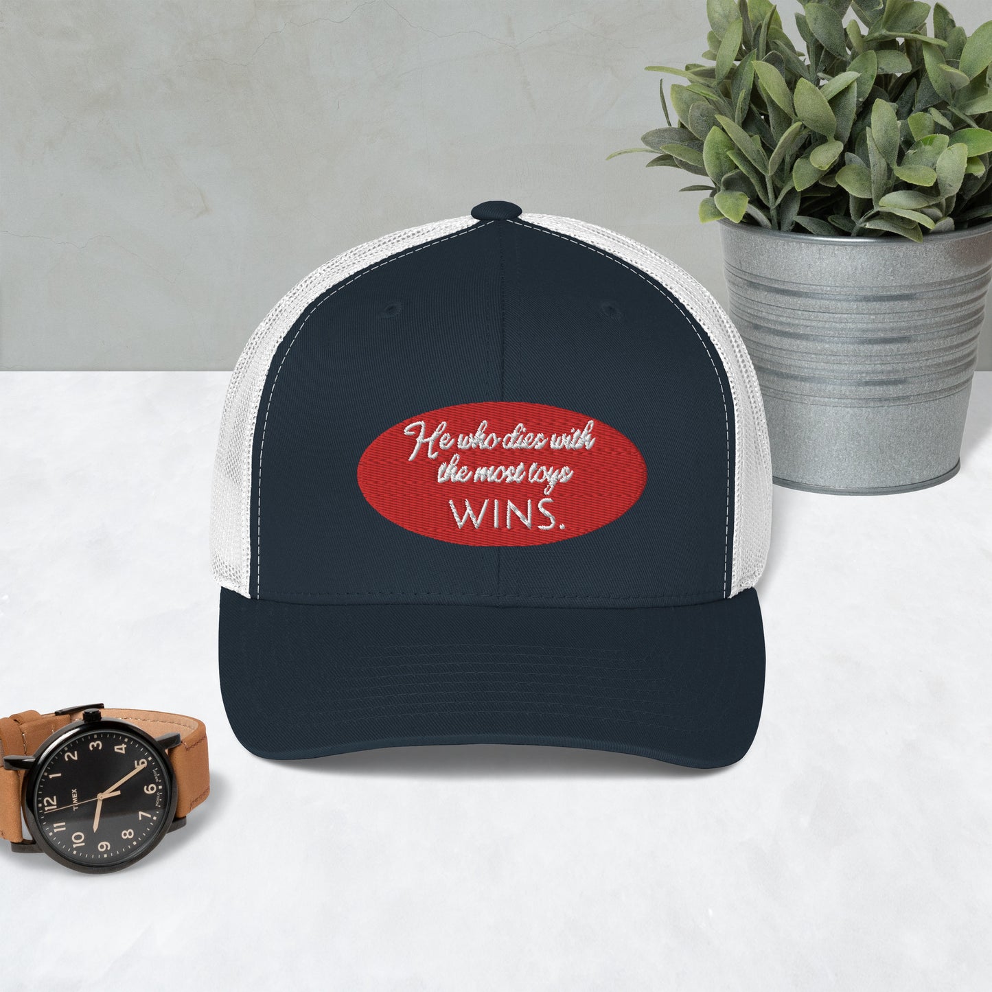 He who dies with the most toys WINS. Trucker Cap