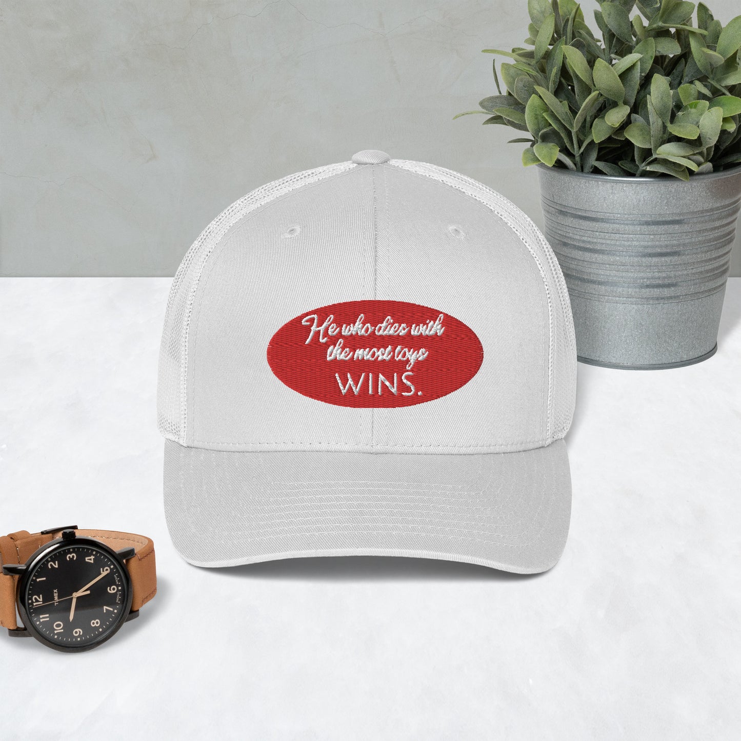 He who dies with the most toys WINS. Trucker Cap